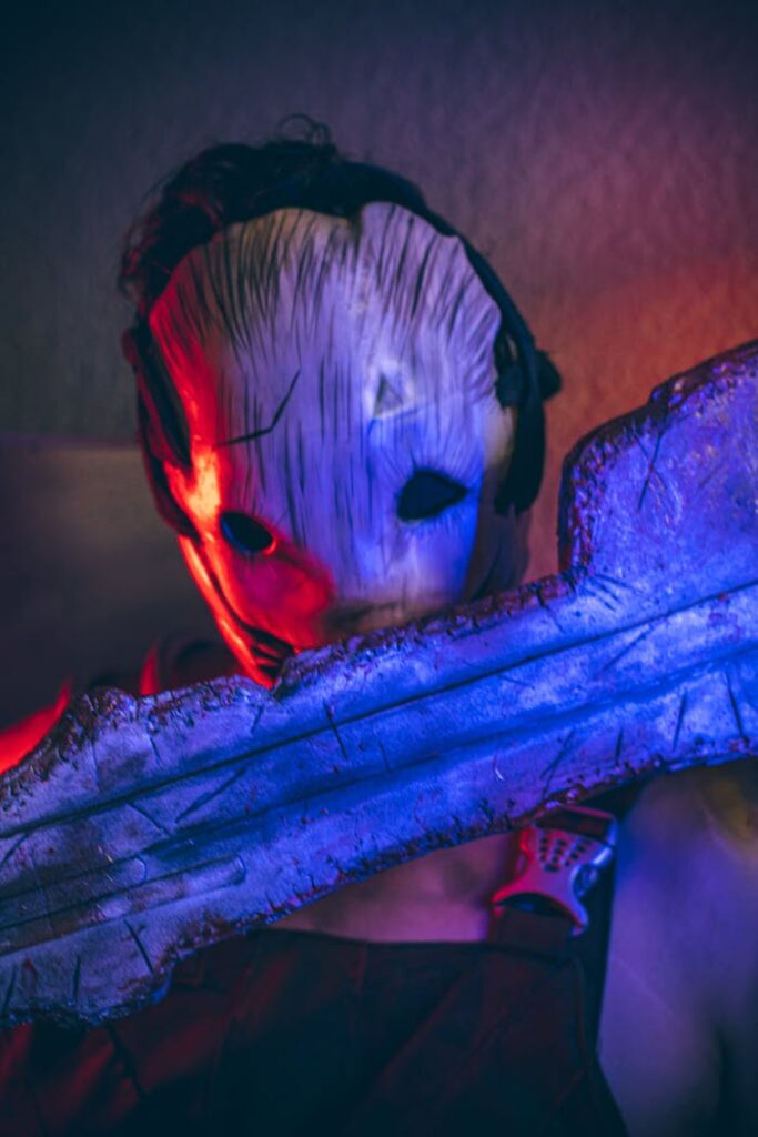 Close-up of a person in a scary Halloween mask, vibrant lighting.
